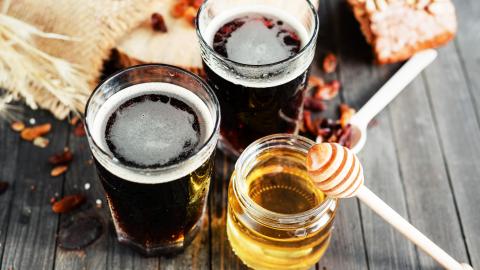 Zwei Gläser Honigbier und Honigglas auf
                                          Tisch