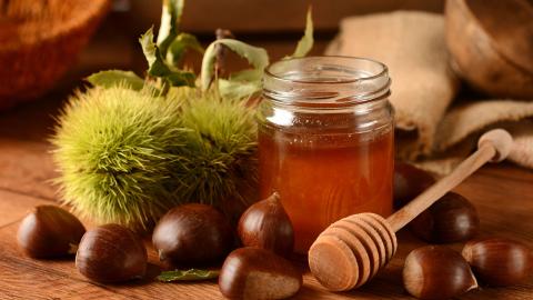 Kastanienhonig im Glas neben Kastanien
