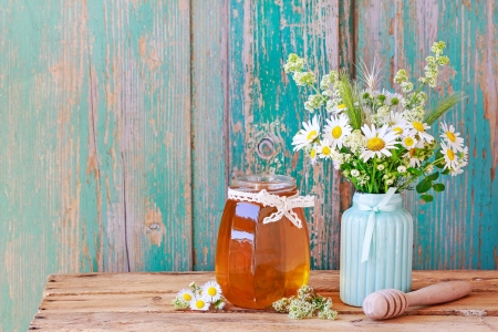 Blütenhonig im Glas neben Blumenstrauß