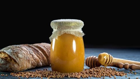 Buchweizenhonig neben Brot auf Tisch