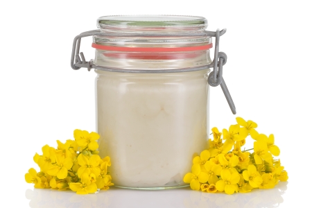 Weißer Honig im Glas neben Blüten