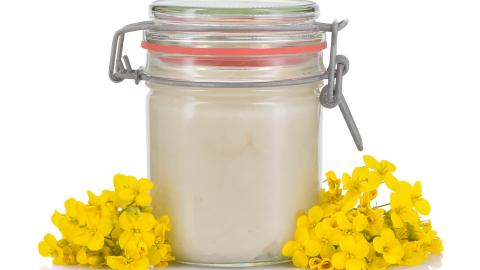 Weißer Honig im Glas neben Blüten